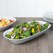 A bowl of salad with spinach, tomatoes, and other vegetables in an American Metalcraft oblong melamine bowl.