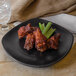 A Nara black matte square melamine plate with chicken wings and celery