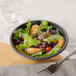 A bowl of salad with shrimp and lettuce in a black matte melamine bowl.