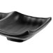 A black square sauce dish with curved edges.