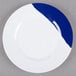 A close-up of a white melamine plate with a wide navy blue rim.
