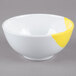 A white melamine bowl with a yellow rim.