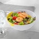 A white melamine bowl filled with salad, shrimp, and tomatoes.