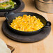 A Lodge mini cast iron casserole dish of macaroni and cheese with a side of bread on a table in a farm-to-table restaurant.