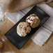 A black rectangular melamine platter with a cookie on it.