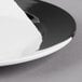 A close-up of a GET white melamine plate with a black and white rim.