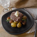 A Nara black matte square melamine plate with a steak and potatoes on it.