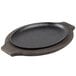 A black oval pan with a black handle on a wooden stand.