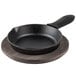 A Lodge cast iron skillet with a walnut wood underliner and black silicone handle holder on a wooden table.