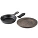 A Lodge black cast iron skillet with a walnut wood underliner and black silicone handle holder on a table.