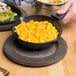 A person holding a Lodge mini cast iron skillet with macaroni and cheese.