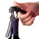 A hand using a Franmara EasyPro waiter's corkscrew to open a wine bottle.