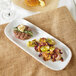 A rectangular melamine platter with a plate of food including meat and vegetables on a table.