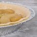 An apple pie in a D&W Fine Pack foil pie pan on a bakery counter.