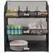 A black steel mesh rack with 3 compartments for coffee condiments.