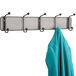 A Safco Onyx steel mesh coat rack with a blue coat hanging on it.
