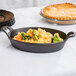 An American Metalcraft pre-seasoned mini cast iron oval casserole dish filled with food on a table.