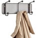 A Safco Onyx steel mesh wall coat rack with a coat hanging on it.