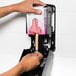 A hand using a Kutol Soft & Silky black bag-in-box hand soap dispenser.
