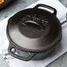 A Lodge black cast iron Dutch oven with a lid on a white napkin.
