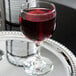 A Libbey red wine glass on a silver tray with a glass of red wine.