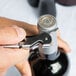 A person opening a bottle of wine with a Franmara Duo-Lever corkscrew.