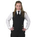 A woman wearing a black Henry Segal server vest and tie over a white shirt.