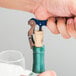 A person using a Franmara Duo-Lever corkscrew with a blue enamel handle to open a bottle of wine.