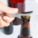 A hand using a Franmara stainless steel waiter's corkscrew to open a bottle of beer.