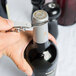 A person using a Franmara curved stainless steel waiter's corkscrew to open a bottle of wine.