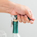 A hand using a Franmara Duo-Lever corkscrew with a green enamel handle to open a bottle of wine with a cork stopper.