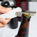 A person using a Franmara Boomerang Waiter's Corkscrew with a white handle to open a bottle on a counter.