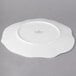 A white Villeroy & Boch bone porcelain plate with a small flower design on a gray surface.