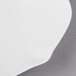 A close-up of a Villeroy & Boch white bone porcelain flat plate with a curved edge on a gray surface.