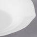 A close up of a Villeroy & Boch white bone porcelain bowl with a curved edge.