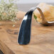 A Bon Chef stainless steel bouillon tasting spoon on a wood surface.