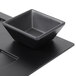 A black square bowl on a black surface.