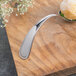 A Bon Chef Tuscany bouillon tasting spoon with food on it sitting on a table.
