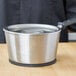 A silver Vollrath stainless steel pot with a lid on a wooden surface.