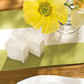 A table setting with Villeroy & Boch white porcelain pepper shakers on a table with a yellow flower.