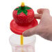 A person holding a Sparkle Strawberry Top Souvenir Cup with a straw in it.