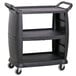 A Carlisle black plastic utility cart with three shelves and wheels.