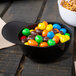 A black mini baseball helmet bowl filled with candy on a table.