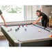 A woman playing pool with a man on a Mizerak pool table.