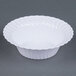A white Fineline Flairware plastic bowl with a wavy edge.