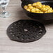A Lodge cast iron trivet under a black skillet of potatoes on a table.