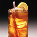 A glass of iced tea with a straw and a lemon slice on a table with ice.