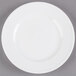 A Libbey Alpine White Porcelain Plate with a rim on a gray surface.