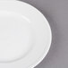 A close-up of a Libbey alpine white porcelain plate with a white rim on a gray surface.