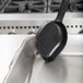 A black Vollrath High Heat Solid Oval Nylon Spoodle on a metal tray.
